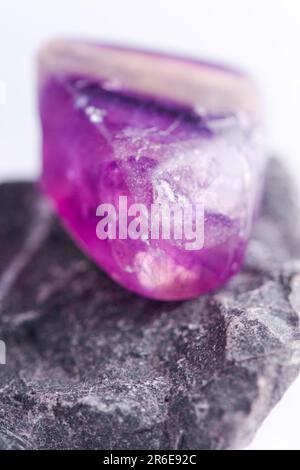 Natursteinamethyst glänzt in wunderschönen Farben auf weißem Hintergrund Stockfoto