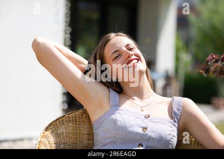 Junge Frau, die im Garten sitzt Stockfoto