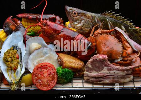 Eine Platte mit verschiedenen Meeresfrüchten und Fleisch wird auf einem weißen Teller serviert Stockfoto