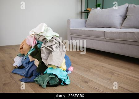 Stapel von achtlos verstreut Kleidung auf dem Boden. Stockfoto