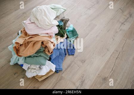Stapel von achtlos verstreut Kleidung auf dem Boden. Stockfoto