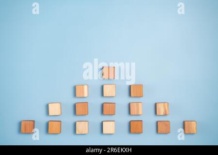 Leere Holzwürfel in Pyramidenfarben von dunkel bis hellbeige auf blauem Hintergrund. Minimalistische abstrakte Konzeptdarstellung des Fortschritts A. Stockfoto