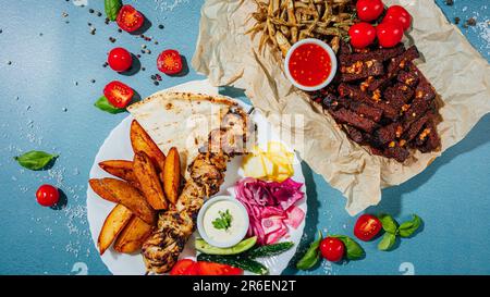 Zwei Teller mit frisch zubereiteter Küche, jeweils mit saftigem gegrilltem Fleisch, goldenen Kartoffelschnitzeln und reifen Tomaten, bereit zum Genießen Stockfoto