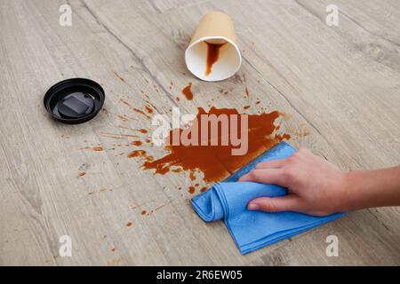 Pappbecher Kaffee fiel auf Laminat, Kaffee verschüttete auf den Boden. Stockfoto