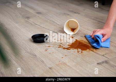 Pappbecher Kaffee fiel auf Laminat, Kaffee verschüttete auf den Boden. Stockfoto