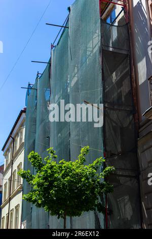 Restaurierung des Gebäudes. Gerüst und schützendes grünes Gebäudegeflecht. Sicherheitstechniken bei Bauarbeiten. Stockfoto