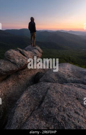 Auf dem Gipfel des Old Rag im Shenandoah-Nationalpark, Virginia, steht ein Wanderer bei Sonnenaufgang auf einem Felsen. Stockfoto