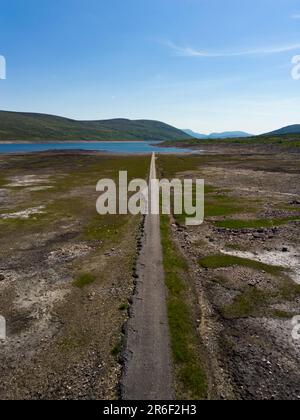 Garve, Schottland, Großbritannien. 9. Juni 2023 Niedrige Wasserstände im Loch Glascarnoch Reservoir nahe Garve südlich von Ullapool haben die Route der alten Straße von Ullapool nach Dingwall offenbart. Die Straße und die Brücken werden normalerweise unter Wasser getaucht, doch haben die jüngsten Dürrebedingungen zu Warnungen vor möglichen Wasserbeschränkungen geführt. Iain Masterton/Alamy Live News Stockfoto