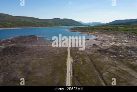 Garve, Schottland, Großbritannien. 9. Juni 2023 Niedrige Wasserstände im Loch Glascarnoch Reservoir nahe Garve südlich von Ullapool haben die Route der alten Straße von Ullapool nach Dingwall offenbart. Die Straße und die Brücken werden normalerweise unter Wasser getaucht, doch haben die jüngsten Dürrebedingungen zu Warnungen vor möglichen Wasserbeschränkungen geführt. Iain Masterton/Alamy Live News Stockfoto