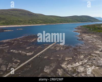 Garve, Schottland, Großbritannien. 9. Juni 2023 Niedrige Wasserstände im Loch Glascarnoch Reservoir nahe Garve südlich von Ullapool haben die Route der alten Straße von Ullapool nach Dingwall offenbart. Die Straße und die Brücken werden normalerweise unter Wasser getaucht, doch haben die jüngsten Dürrebedingungen zu Warnungen vor möglichen Wasserbeschränkungen geführt. Iain Masterton/Alamy Live News Stockfoto