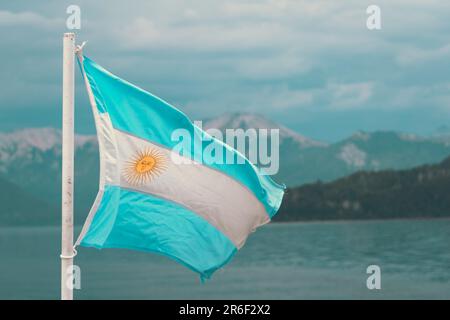 Eine pulsierende argentinische Flagge, die im Wind über einem ruhigen blauen Gewässer fliegt Stockfoto