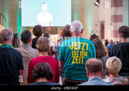 09. Juni 2023, Bayern, Fürth: Besucher während des von KI geschaffenen Gottesdienstes. Ein Besucher-T-Shirt zeigt den Kirchentag-Slogan „Now is the Time“. In St. Paul Church, ein Service, der vom KI-Chat-GPT erstellt und zuvor aufgezeichnet wurde, wird durchgeführt. Foto: Daniel Vogl/dpa/Alamy Live News Stockfoto