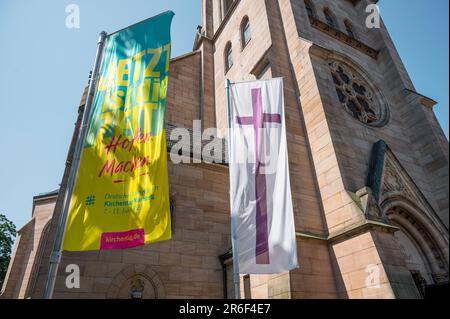 09. Juni 2023, Bayern, Fürth: Eine Flagge des Deutschen Evangelischen Kirchenkongresses und die Kirchenflagge der Evangelischen Kirche hängen vor dem St. Paul Church. Ein Service, der von der künstlichen Intelligenz (AI) Chat GPT erstellt wurde und zuvor aufgezeichnet wurde, wird in St. Paul Church. Foto: Daniel Vogl/dpa/Alamy Live News Stockfoto