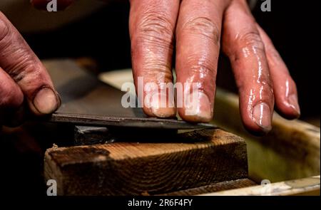 Eine Nahaufnahme eines rostigen Messers, das gegen einen Metallblock geschärft wurde Stockfoto