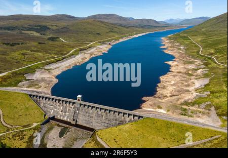 Garve, Schottland, Großbritannien. 9. Juni 2023 Der Glascarnoch-Damm südlich von Ullapool aus der Vogelperspektive. Die anhaltende Dürre in den schottischen Highlands hat zu niedrigen Wasserständen im Glascarnoch-Reservoir bei Garve geführt. Die Behörden haben vor möglichen Wasserbeschränkungen gewarnt, falls das Wetter weiterhin trocken ist. Iain Masterton/Alamy Live News Stockfoto