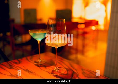 Zwei köstliche eiskalte Cocktails in exquisiten Gläsern stehen auf einem Holztisch in einem Restaurant. Alkoholische Getränke im Hintergrund des Cafés mit Rechnung Stockfoto