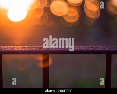 Ein verschwommenes Foto des Sonnenuntergangs hinter einem Zaun. . Stockfoto