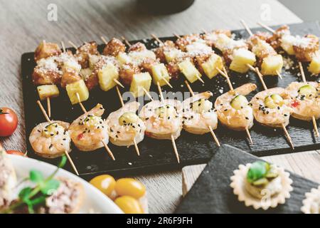 Eine Auswahl an Vorspeisen, darunter Oliven, Käse und verschiedene Gemüsesorten, die auf einem Holzbrett angeordnet sind Stockfoto