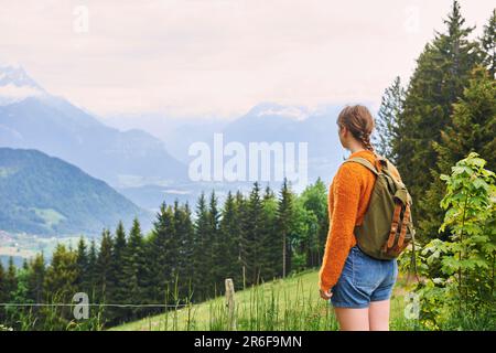 Junge Mädchen wandern in den Bergen, genießen das fantastische Tal von oben, tragen einen Rucksack, Rückblick Stockfoto