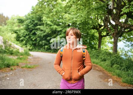 Außenporträt eines glücklichen Jungen mit Rucksack im Green Park Stockfoto