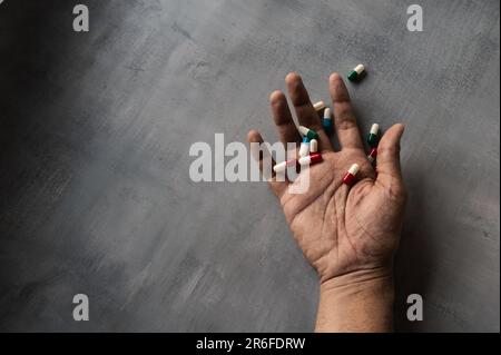 Nahaufnahme von Hand und Pillen auf Betonboden mit Kopierraum. Uberdosis, Drogenabhängiger und Suizidkonzept Stockfoto