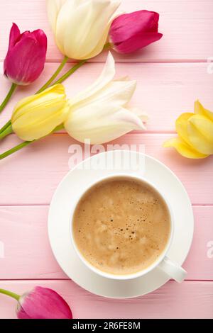 Tasse Kaffee mit Tulpen auf pinkfarbenem Hintergrund und Kopierbereich. Draufsicht Stockfoto