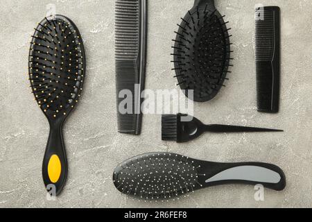 Haarwerkzeuge, Schönheits- und Friseurkonzept – verschiedene Bürsten oder Kämme auf grauem Hintergrund. Draufsicht Stockfoto