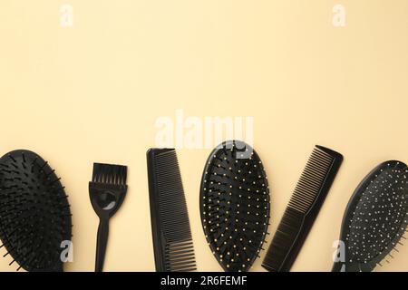 Haarwerkzeuge, Schönheits- und Friseurkonzept - verschiedene Bürsten oder Kämme auf beigefarbenem Hintergrund. Draufsicht Stockfoto