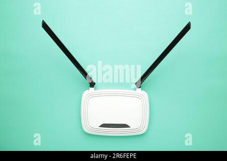 Weißer wlan-Router mit schwarzen Antennen auf mintfarbenem Hintergrund mit Kopierbereich. Minimalismus. Draufsicht Stockfoto