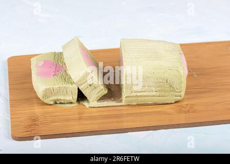 Pistazieneis in Scheiben mit einer herzförmigen Himbeerschicht auf einem Schneidebrett. Speicherplatz kopieren. Stockfoto