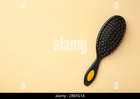 Haarbürste mit schwarzem Griff auf beigefarbenem Hintergrund. Draufsicht Stockfoto