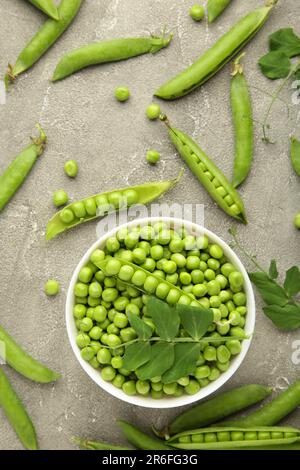 Grüne Erbse in der Schüssel auf grauem Hintergrund. Frisches Bio-Gemüse. Draufsicht. Stockfoto