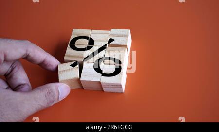 Ordnen Sie Holzwürfel mit dem Prozentzeichen von Hand an. Konzept der Umschuldung, Darlehensrefinanzierung und Schuldenrückzahlung Stockfoto