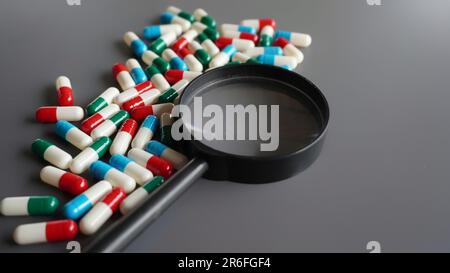 Vergrößerungsglas und Medizinpillen. Gefälschte Medikamente, Pillen analysieren und untersuchen Konzept Stockfoto