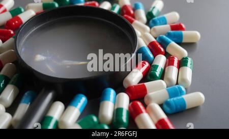 Vergrößerungsglas und Medizinpillen. Gefälschte Medikamente, Pillen analysieren und untersuchen Konzept Stockfoto
