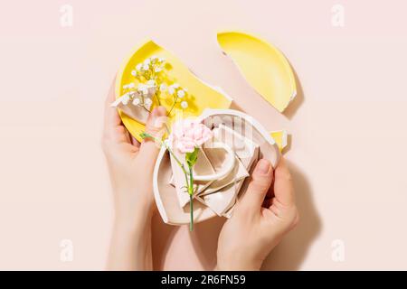 Weibliche Hände halten Teile einer kaputten Platte auf rosa Hintergrund Stockfoto