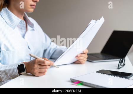 Eine Managerin sitzt an einem Tisch im Büro und liest einen Vertrag. Stockfoto