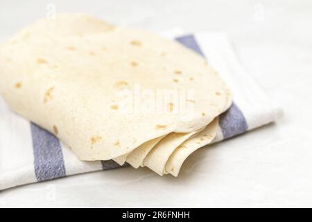 Ein weißes Handtuch auf einem Holztisch mit zwei separaten Stücken frisch gebackenem Brot Stockfoto