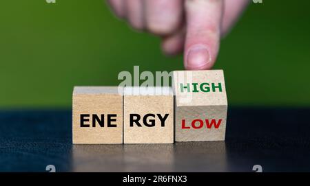 Die Hand dreht Würfel und ändert den Ausdruck „Energie niedrig“ in „Energie hoch“. Stockfoto