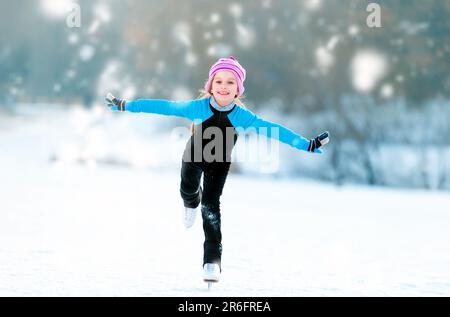 Fröhliches, süßes Mädchen in Thermalanzügen, Schlittschuhlaufen Stockfoto