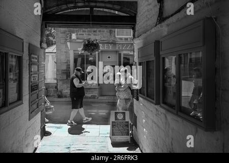 Die Leute gehen entlang der Hauptstraße der Pateley Bridge, die sich neben dem Eingang zum Kings Court Shopping Courtyard in Nidderdale, Großbritannien, befindet. Stockfoto