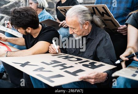 Verschiedene Aktivisten mit unterschiedlichem Alter und unterschiedlicher ethnischer Zugehörigkeit, die Protestbanner gegen Finanzkrise und globale Inflation vorbereiten Stockfoto