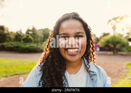 Glückliches junges afrikanisches Mädchen, das Spaß hat, in die Kamera zu lächeln, im öffentlichen Park Stockfoto
