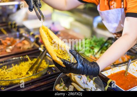 Vietnamesische Frau serviert abends traditionelle vietnamesische Sandwiches Banh mi in Street Food Stockfoto