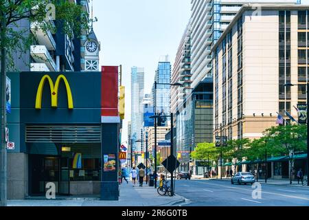 Toronto, Kanada - 4. Juni 2023: Ein McDonald's Restaurant und Logo auf einer Stadtstraße. Passanten laufen am Restaurant vorbei. Stockfoto