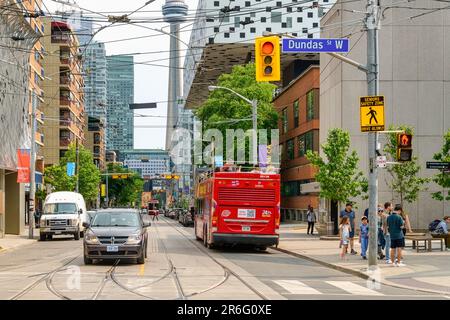 Toronto, Kanada - 4. Juni 2023: Ein roter Tourbus mit offenem Dach mit Passagieren auf der Dundas St. W. der CN-Turm ist im Hintergrund zu sehen. Stockfoto