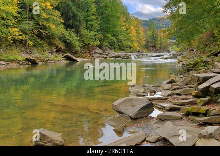 Das Foto wurde in der ukrainischen Stadt Yaremche aufgenommen. Das Foto zeigt eine Herbstlandschaft des Flusses namens Prut in einem bergigen Waldgebiet. Stockfoto