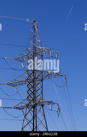 Frostbedeckter Power-Line-Pylon an einem klaren, frostigen Tag vor blauem Himmel Stockfoto