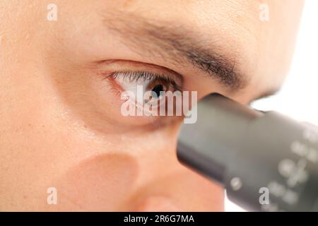 Professioneller männlicher Wissenschaftler, der im Labor durch das Mikroskop schaut Stockfoto