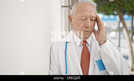 Leitender grauhaariger Arzt, der auf der Straße Kopfschmerzen hat Stockfoto